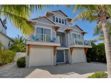 Coastal home featuring two-car garage, covered balconies, and tropical landscaping for a relaxing island lifestyle at 212 72Nd, Holmes Beach, FL 34217