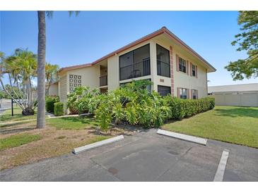 Well-maintained building exterior featuring lush landscaping, a private screened balcony, and ample parking at 2415 Bayshore Gardens Pkwy # 8, Bradenton, FL 34207