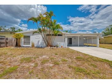 Inviting single-story home featuring a carport and freshly painted exterior with tropical landscaping at 3599 Bali Dr, Sarasota, FL 34232