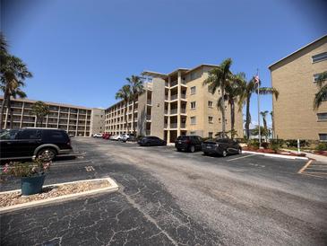 View of the tan building featuring multiple floors, palm trees, and plenty of parking spaces at 3647 Lake Bayshore Dr # 416, Bradenton, FL 34205