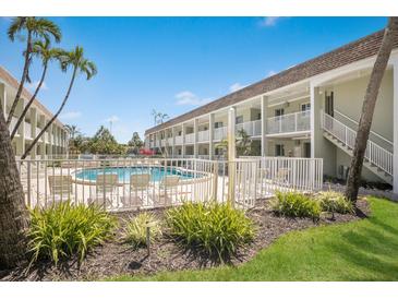 Exterior view of a community pool surrounded by lush landscaping and a multi-story condo building at 7100 Gulf Dr # 114, Holmes Beach, FL 34217