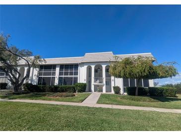 White condo building with large windows, arched entry, manicured lawn, and mature trees at 1613 Southwood St # 1613, Sarasota, FL 34231