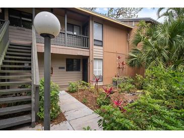 Inviting condo exterior with lush landscaping and well-maintained facade and walkway to stairs at 1703 Pelican Cove Rd # 356, Sarasota, FL 34231