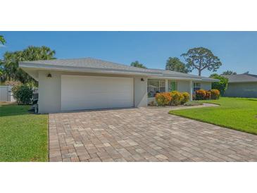 Charming single-story home with a brick driveway, two-car garage, and vibrant landscaping at 1857 Jasmine Dr, Sarasota, FL 34239