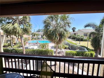 Balcony view of a community pool surrounded by lush tropical landscaping and well-maintained walkways at 3447 Clark Rd # 246, Sarasota, FL 34231