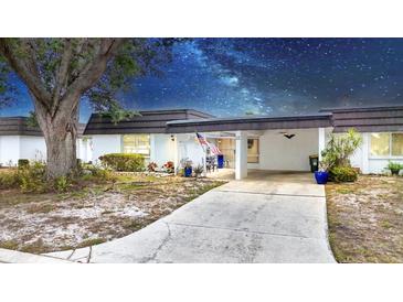 Charming single-story home featuring a covered carport and a welcoming front patio with decorative plants and an American flag at 3941 Glen Oaks E Dr # 32, Sarasota, FL 34232