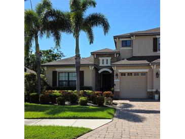 Charming two-story home features lush landscaping, a brick driveway, and a welcoming entrance with stone accents at 535 Honeyflower Loop, Bradenton, FL 34212