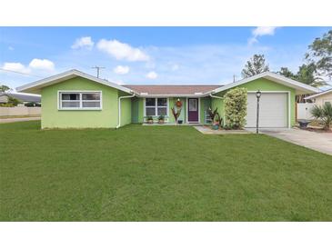 Charming, one-story home with a lush green lawn, bright green exterior, and attached one car garage at 5353 Starwood Pl, Sarasota, FL 34232
