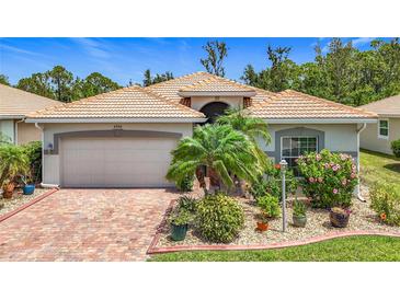 Charming single-story home featuring a beautiful terracotta tile roof, two-car garage, and lush landscaping at 6240 Falcon Lair Dr, North Port, FL 34287
