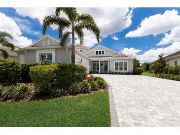 Beautiful, light grey two-story home with a large palm tree and paved driveway at 8133 Grande Shores Dr, Sarasota, FL 34240