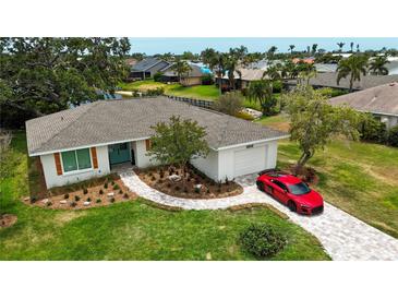 Charming single-story home featuring a lush lawn, a paver walkway, and a red sports car in the driveway at 8808 44Th Avenue W Dr, Bradenton, FL 34210