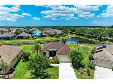 Aerial view of a single Gathering home featuring a well-manicured lawn, mature landscaping, and a serene pond at 12815 24Th Street E Cir, Parrish, FL 34219