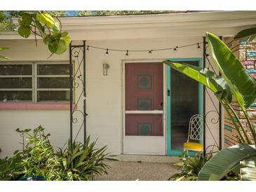 Charming home entrance with decorative screen door, teal accents, and lush tropical landscaping at 2207 Hickory Ave, Sarasota, FL 34234
