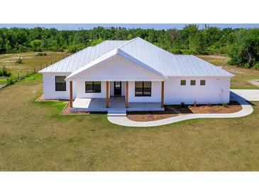 Charming one-story home featuring a metal roof, welcoming front porch, and meticulously landscaped yard at 27510 67Th E Ave, Myakka City, FL 34251