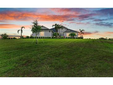 Beautiful single-story home with lush green lawn and tropical palm trees under a colorful sunset sky at 3518 Recurve Cir, Sarasota, FL 34240