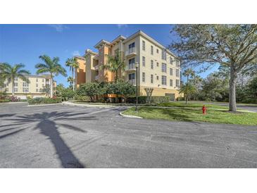 Beautiful building with landscaped grounds, palm trees, and plenty of parking on a sunny day at 6465 Watercrest Way # 404, Lakewood Ranch, FL 34202