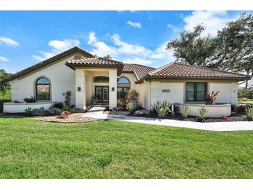 Charming single-story home featuring a tile roof and a beautifully landscaped front yard with fresh green grass at 8950 Misty Creek Dr, Sarasota, FL 34241