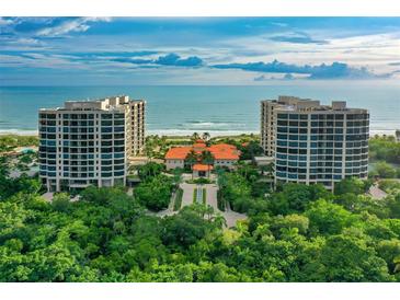Stunning aerial view of beachfront condos with manicured grounds and direct access to a beautiful sandy beach at 1241 Gulf Of Mexico Dr # 803, Longboat Key, FL 34228