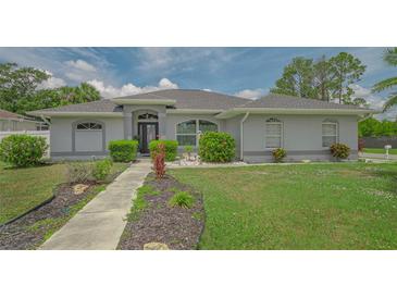 Charming single-story home with manicured lawn and lush landscaping, creating inviting curb appeal at 4037 Wooley Ave, North Port, FL 34287