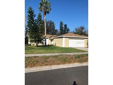 Charming single-story home featuring a well-maintained lawn, mature trees, and a two-car garage at 2726 Knoll E St, Palm Harbor, FL 34683