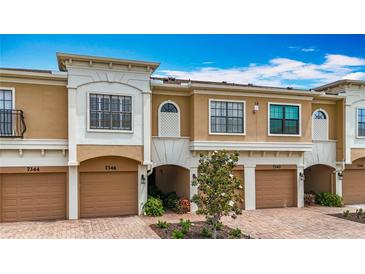 Attractive townhouse showcases an attached garage, well maintained landscaping, and tan and white exterior paint at 7346 Skybird Rd # 417, Bradenton, FL 34209