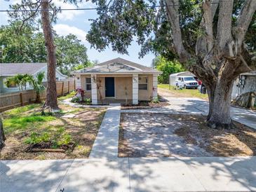 Charming home featuring stucco exterior, dark blue door, decorative pillar accents, and large mature trees at 2411 5Th Avenue E Dr, Palmetto, FL 34221