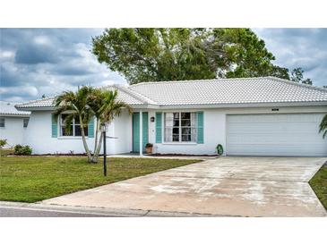 Charming single-story home featuring a white tile roof, attached garage, and well-maintained landscaping at 4102 Lakewood Ave, Bradenton, FL 34208