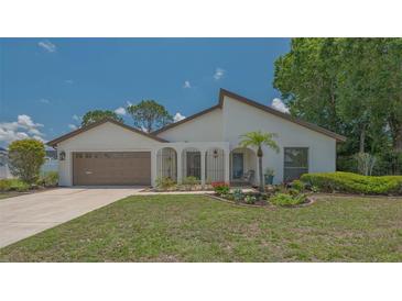 Inviting single-story home featuring a well-manicured lawn, mature trees, and an attached two-car garage at 4812 Greywood Ln, Sarasota, FL 34235