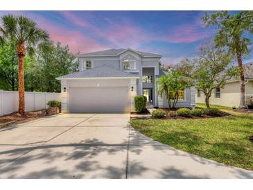 Charming two-story home featuring a manicured front yard, mature trees, and an attached two-car garage at 5561 Burnt Branch Cir, Sarasota, FL 34232