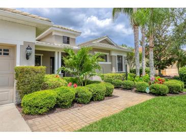 Beautifully landscaped front yard with lush greenery and a brick walkway leading to the home at 6470 Indigo Bunting Pl, Lakewood Ranch, FL 34202
