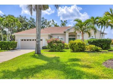 Landscaped front yard of home with lush green lawn and beautiful tropical plants creates curb appeal at 8604 15Th Nw Ave, Bradenton, FL 34209