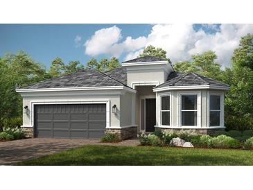 Inviting single-story home featuring a gray roof, stone accents, and a well-manicured lawn at 16404 Isola Pl, Bradenton, FL 34211