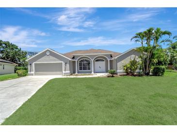 Charming single-story home boasts a manicured lawn and mature palm trees at 168 Wading Bird Dr, Venice, FL 34292