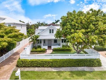 Charming two-story home with a white picket fence and lush landscaping creating a welcoming curb appeal at 1841 Datura St, Sarasota, FL 34239