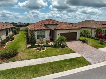 Charming home with a red tile roof, manicured lawn, and a brick paver driveway at 20542 Trattoria Loop, Venice, FL 34293