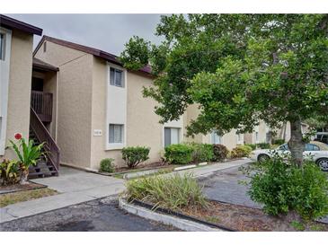 Exterior of a two-story condo building with neutral stucco, a staircase, and landscaping at 2616 Hidden Lake N Dr # A, Sarasota, FL 34237