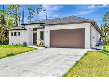Contemporary home showcasing a two-car garage, minimalist landscaping, and light-colored exterior at 3637 Petunia Ter, North Port, FL 34286
