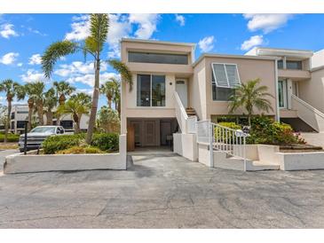 Modern condo featuring covered parking, a stairway to the front door, and lush tropical landscaping at 3803 E Bay Dr # 10, Bradenton Beach, FL 34217