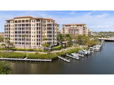 Mediterranean-style building with water views and private boat docks, surrounded by lush landscaping and palm trees at 5531 Cannes Cir # 201, Sarasota, FL 34231