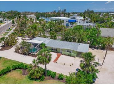 Charming home with a screen enclosed pool surrounded by lush tropical landscaping and a white gravel driveway at 5924 Gulf Of Mexico Dr, Longboat Key, FL 34228