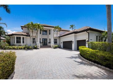 Stately home featuring a barrel tile roof, lush tropical landscaping, and a paver driveway leading to a two-car garage at 6919 Westchester Cir, Lakewood Ranch, FL 34202