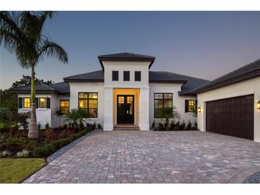 Modern home featuring a well-manicured front yard, a paver driveway, and neutral-toned stucco at 8563 Sea Mist Loop, Sarasota, FL 34240