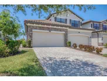 Charming home featuring a brick driveway, two-car garage, and manicured landscaping at 18113 Gawthrop Drive # 101, Lakewood Ranch, FL 34211