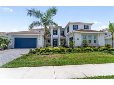 Beautiful two-story home with a well-manicured lawn, blue shutters, and a dark blue garage door at 18215 Cayo Largo Pl, Bradenton, FL 34202