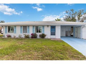 Charming single-story home featuring a bright blue door, light blue shutters, and a well-maintained front lawn at 577 Circlewood Dr # X7, Venice, FL 34293