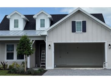 Charming home exterior featuring light siding, a dark roof, dormer windows, and an attached two-car garage at 650 Maldives Trl, Sarasota, FL 34234