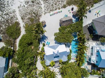 Breathtaking aerial view of a beachfront property with a pool, lush landscaping, and beach access at 102 & 104 48Th St, Holmes Beach, FL 34217