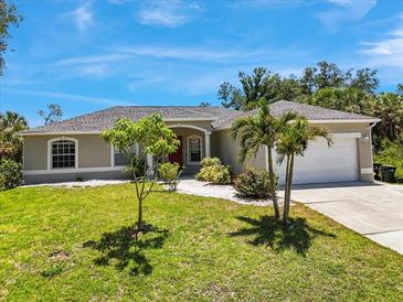 Charming single-story home featuring a well-manicured lawn, beautiful landscaping, and a two-car garage at 1298 Russellville St, North Port, FL 34288