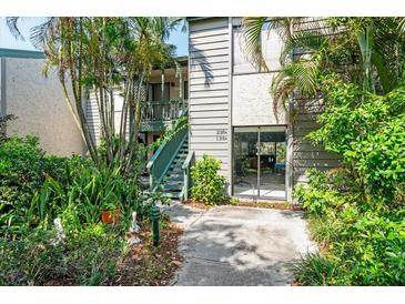 Multi-level condo with lush landscaping, a wooden staircase, and a pathway to the entrance at 1629 Pelican Cove Rd # 138A, Sarasota, FL 34231