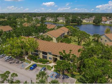 An aerial view of the condo community with waterfront views, ample parking and mature trees at 4037 Crockers Lake Blvd # 17, Sarasota, FL 34238